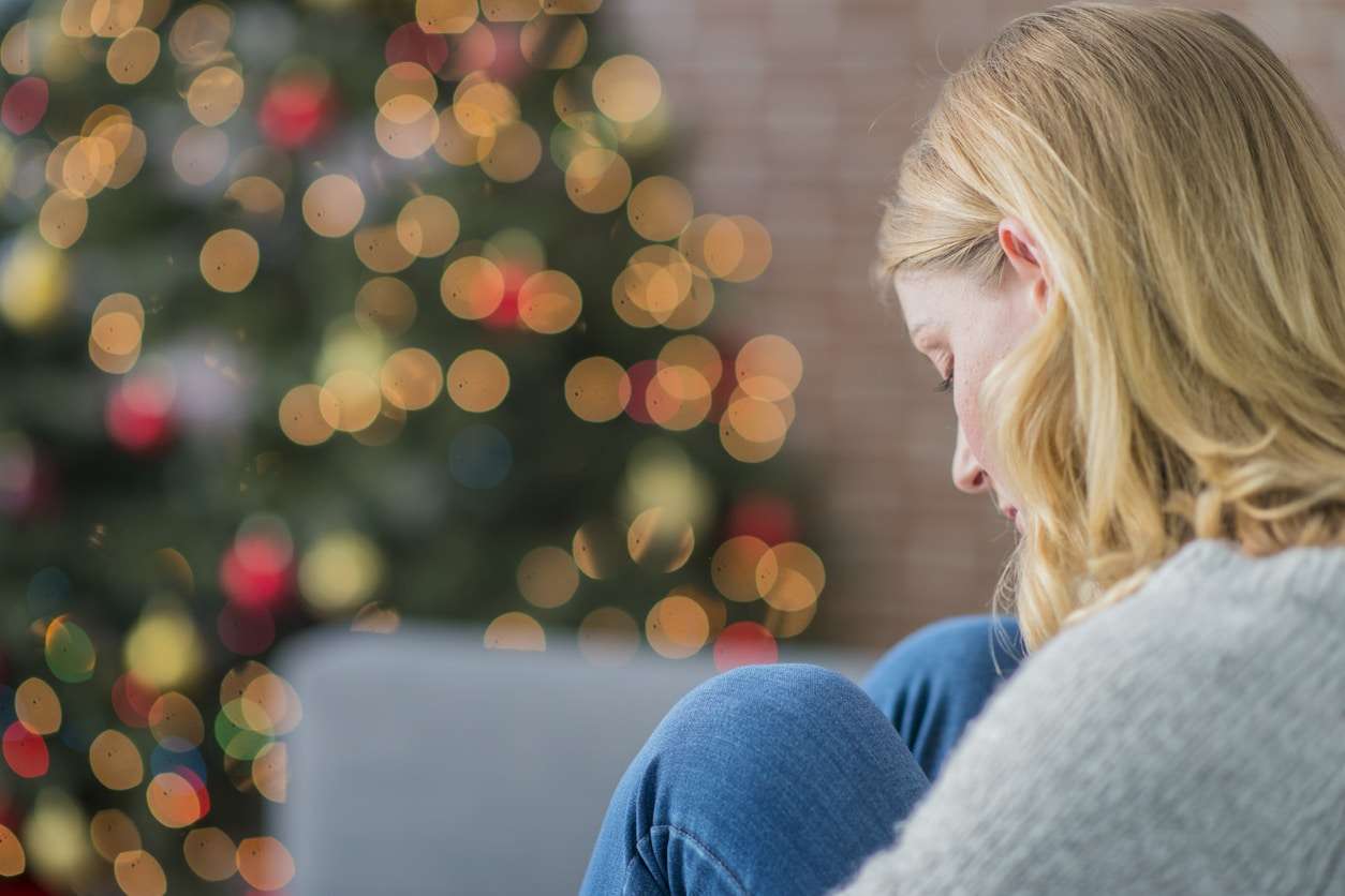 Woman sitting alone on christmas, dealing with holiday depression